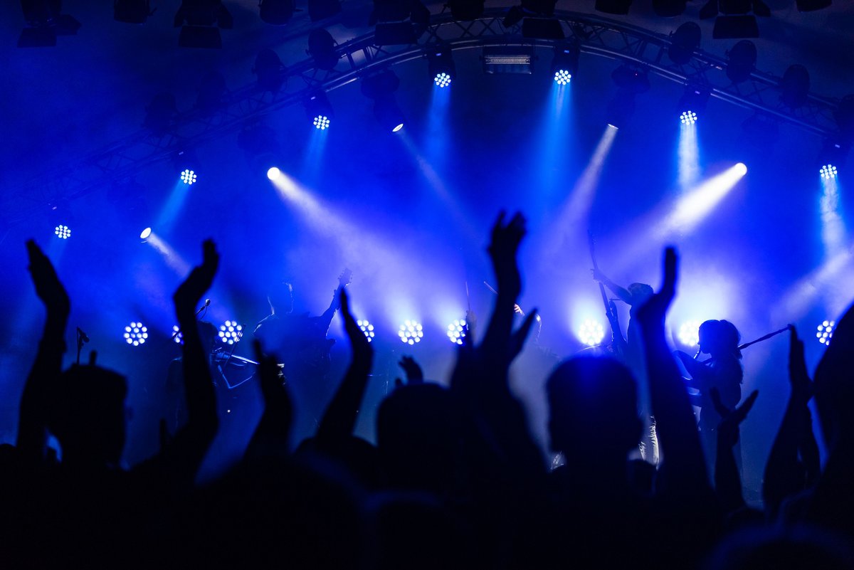 Coachella 2027: Tickets, Preise & Anreise für deutsche Fans 2 Jubelnde Menschenmenge bei einem Musikfestival vor blauer Bühnenbeleuchtung