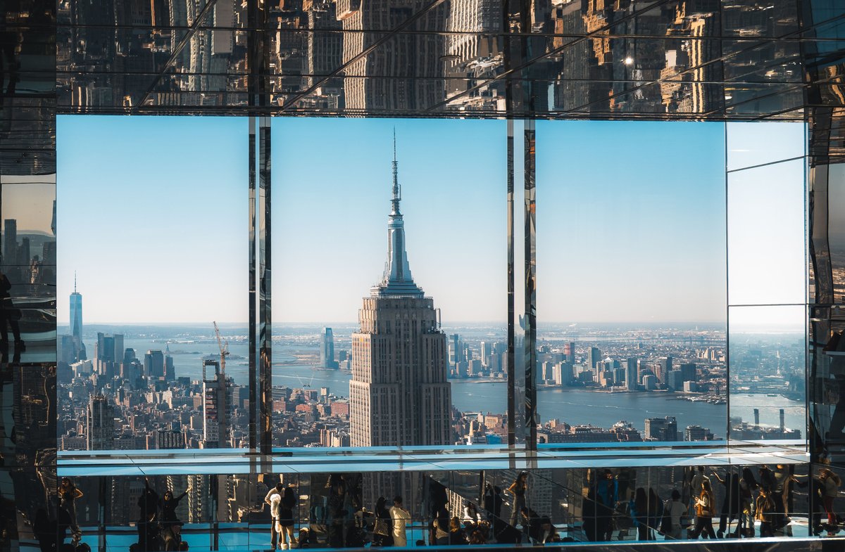 Summit One Vanderbilt Tickets 2026: Preise, Air & Tipps 2 Eine Luftaufnahme des Empire State Building durch reflektierendes Glas, die die ikonische Skyline von New York City einfängt.