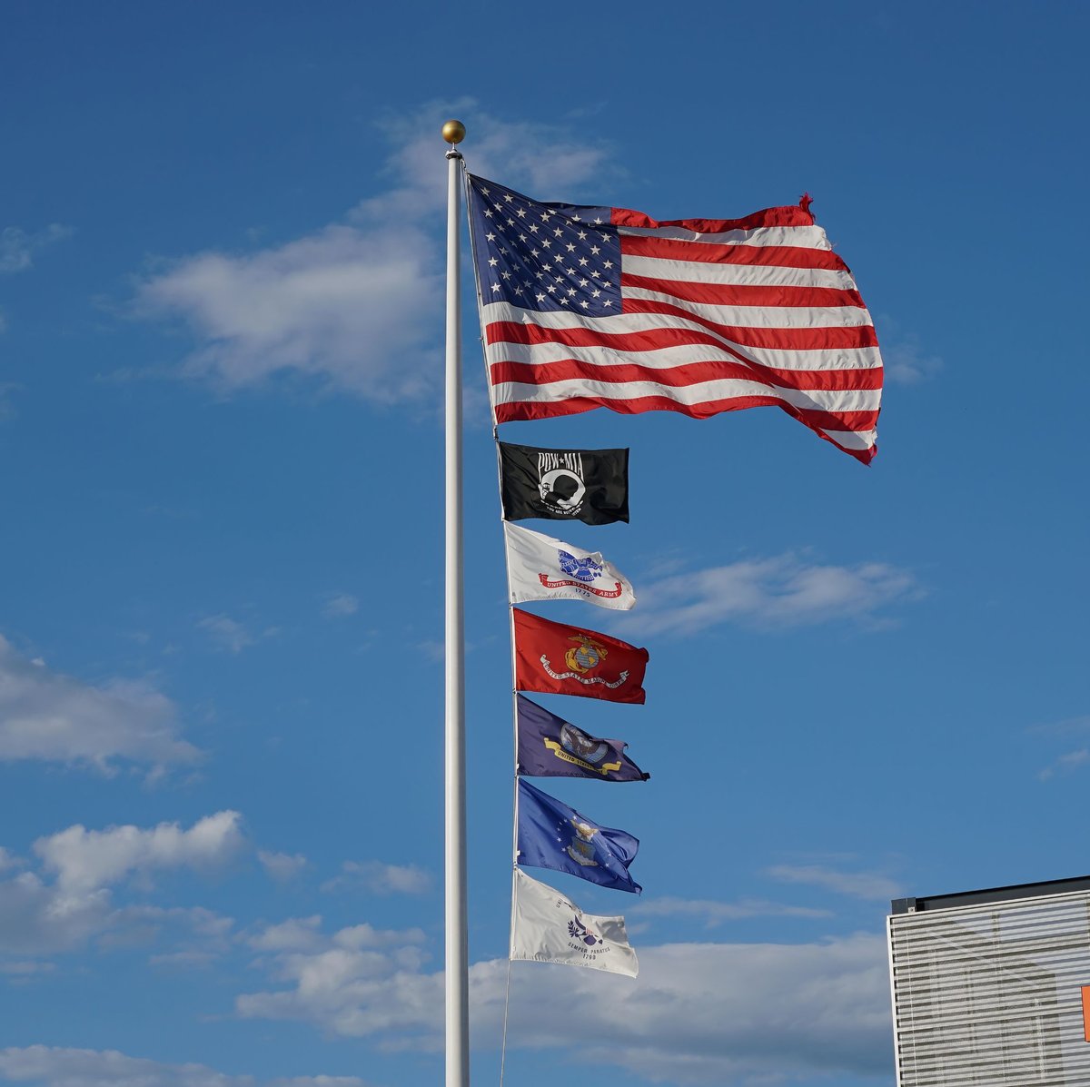 USA-Urlauber Persönlichkeitstest 2026: Welcher Reisetyp bist du? 2 Die amerikanische Flagge und die Militärflaggen wehen unter einem klaren blauen Himmel.